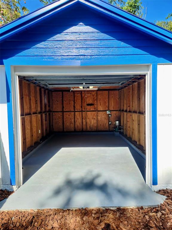 An open, detached garage with blue trim, plywood walls, and a painted concrete floor — 2801 18TH STREET N, ST PETERSBURG, FL