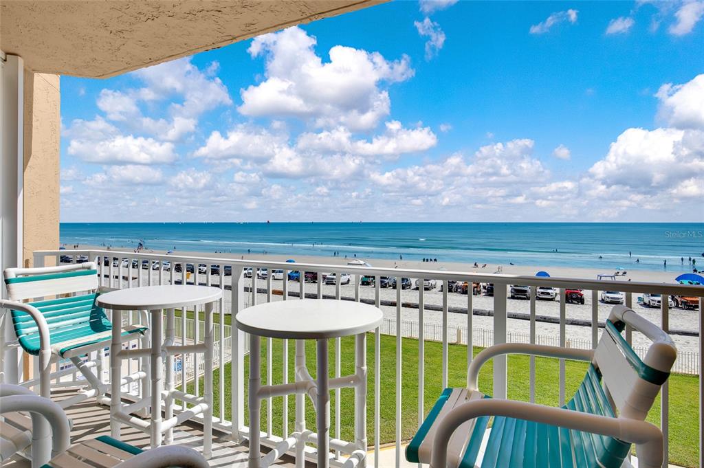 A balcony with white chairs and tables overlooks a sandy beach and the ocean — 421 S ATLANTIC AVENUE UNIT 302, NEW SMYRNA BEACH, FL