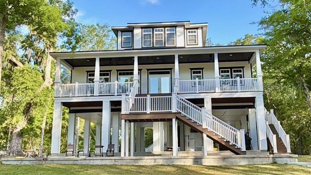 A three-story elevated house with white siding, dark trim, and a large front staircase — 12890 NE 21ST TERRACE, BRANFORD, FL