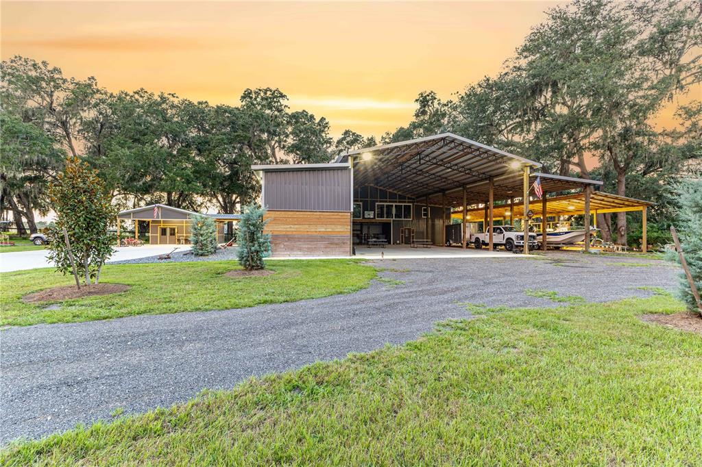 A large metal barn with an open-sided carport and a separate smaller building nearby — 12523 CR 721, WEBSTER, FL