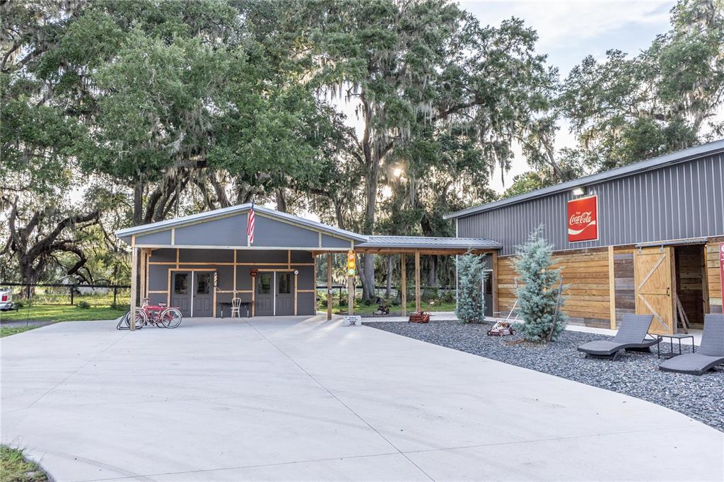 A concrete driveway leads to a metal-sided building with a covered porch and trees — 12523 CR 721, WEBSTER, FL