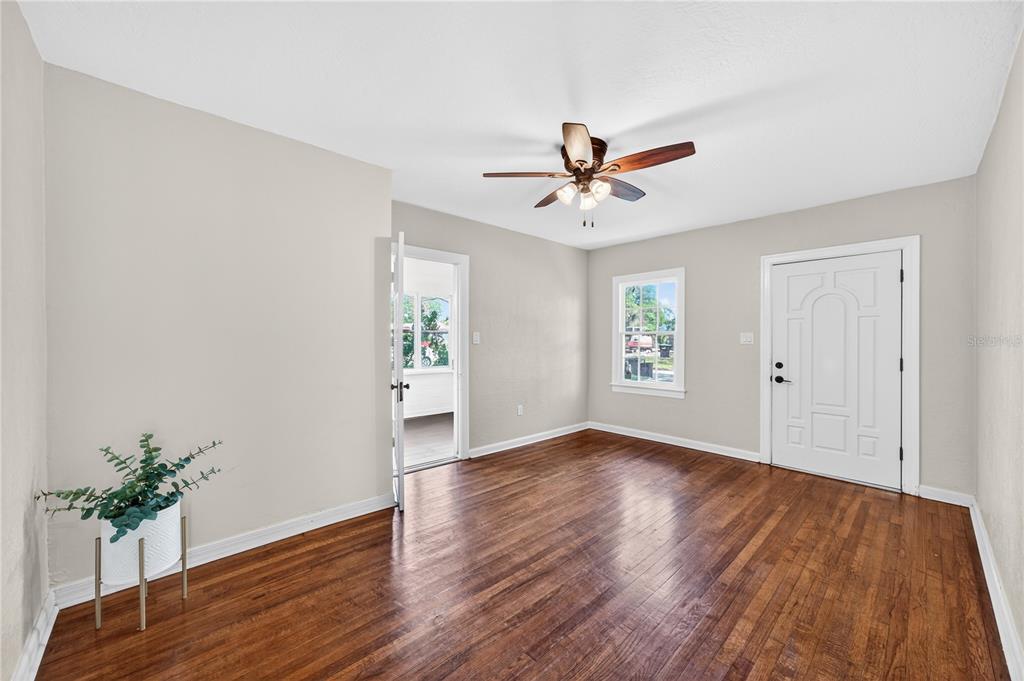 An empty room features hardwood floors, a ceiling fan, a white door, and a window — 2006 CORNELL AVENUE, WINTER PARK, FL