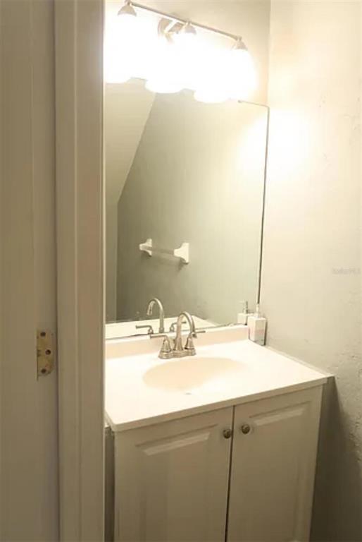 A bathroom vanity with a white cabinet, sink, faucet, and a mirror with overhead lighting — 4415 SW 34TH STREET UNIT 308, GAINESVILLE, FL