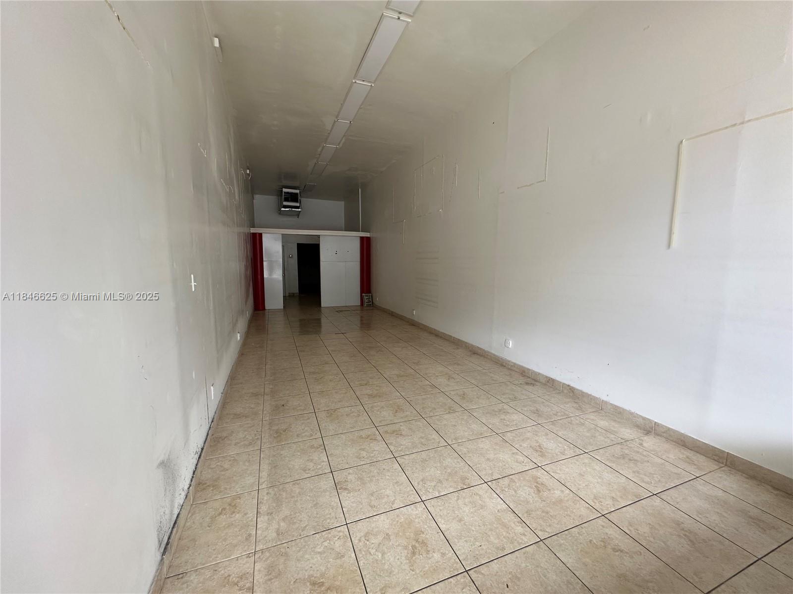 This empty commercial space features white walls, tiled flooring, and a long fluorescent light fixture — 1932 Hollywood Blvd, Hollywood FL 33020, HOLLYWOOD, FL