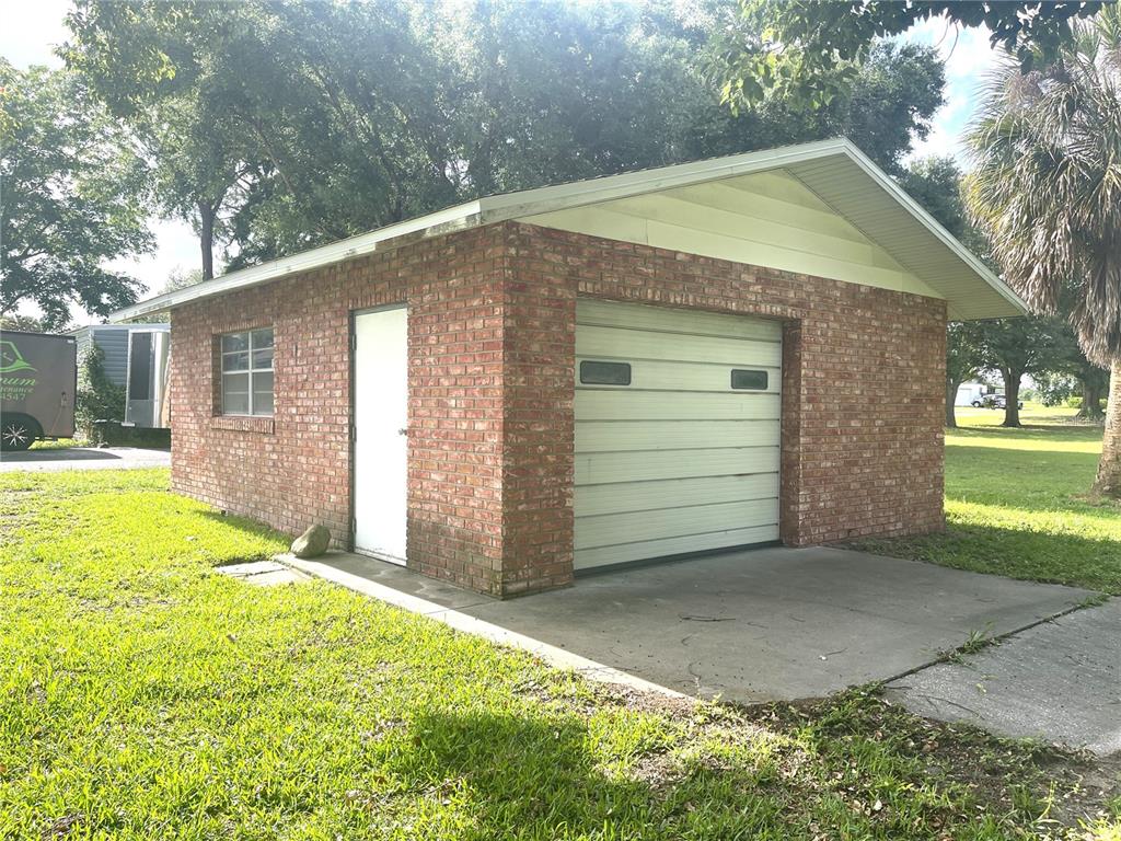 A detached brick garage features a white roll-up door, a side entry door, and a window — 4691 CR 118, WILDWOOD, FL