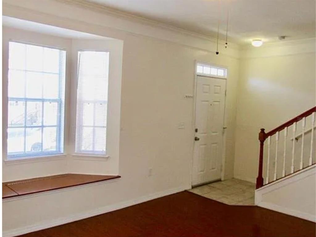 An entryway features a white shoe rack, wall decor, and a staircase with a wooden railing — 6624 TIME SQUARE AVENUE UNIT 104, ORLANDO, FL