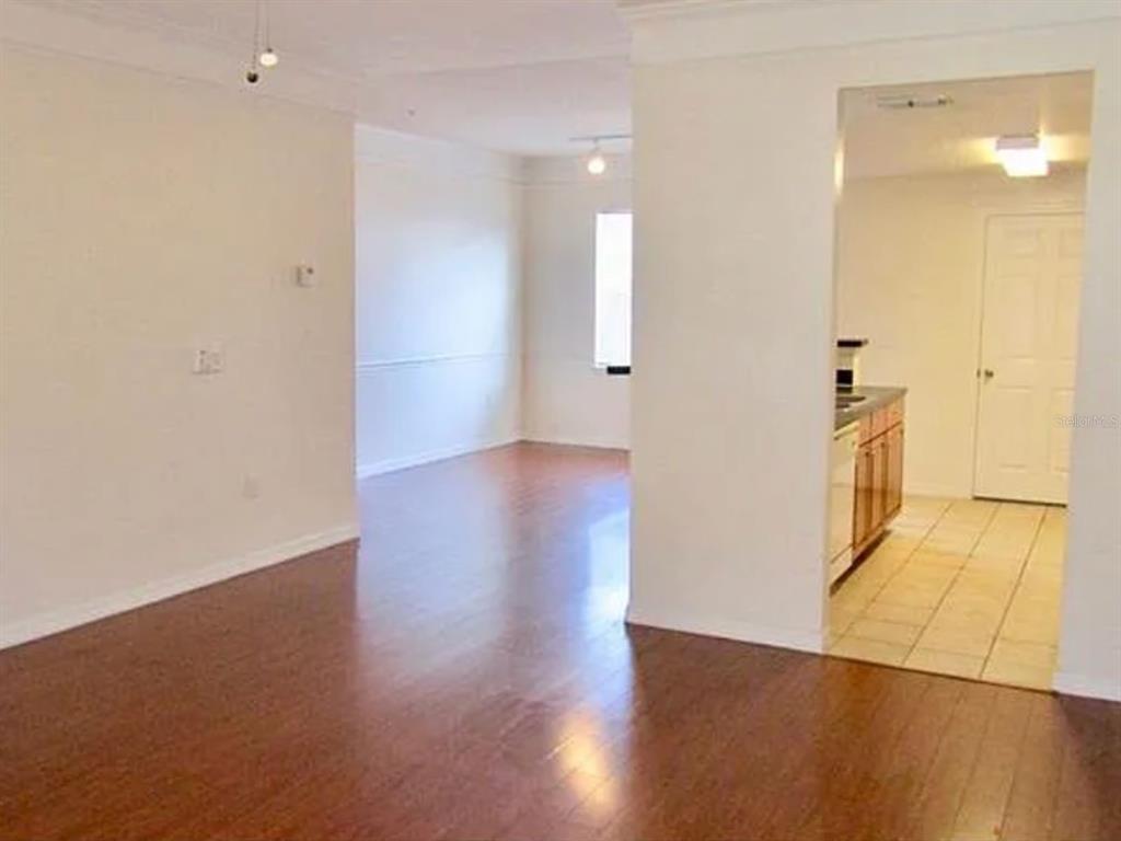 A living room features a large television, a sectional sofa, and a staircase — 6624 TIME SQUARE AVENUE UNIT 104, ORLANDO, FL