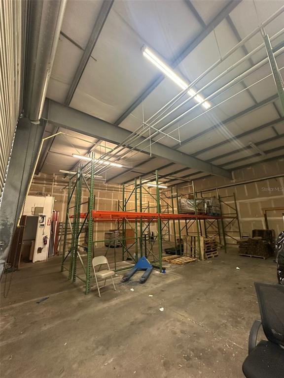 An industrial warehouse space features metal storage racks, a concrete floor, and exposed ceiling lights — 1630 TROPIC PARK DRIVE UNIT 1630, SANFORD, FL