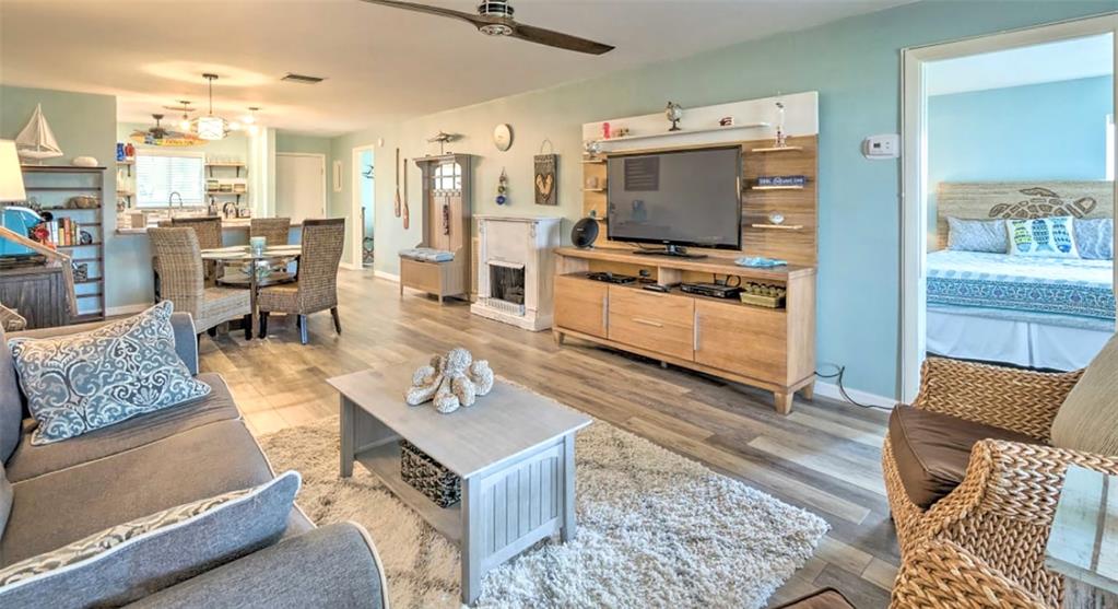 A living room features light wood flooring, a television console, and an adjacent dining area — 777 BEACH ROAD UNIT 1E, SARASOTA, FL