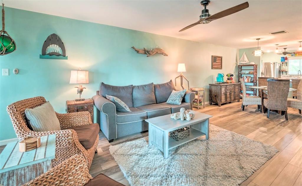 A living room with light blue walls, a gray sofa, and a wicker armchair — 777 BEACH ROAD UNIT 1E, SARASOTA, FL