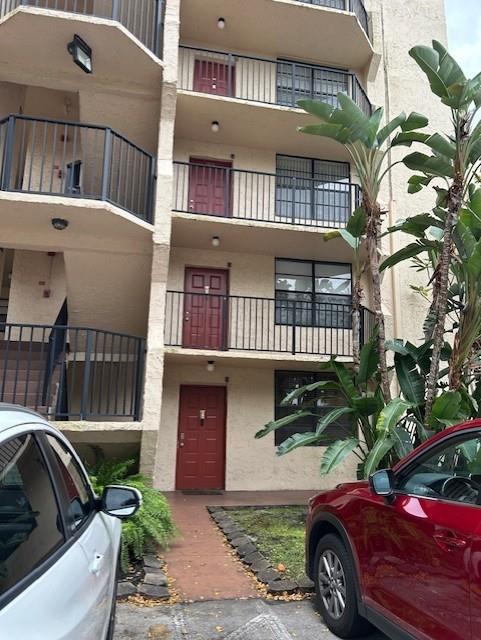 A multi-story apartment building exterior features red doors, black metal railings, and a red car — 3590 Blue Lake Drive # 305, Pompano Beach FL 33064, POMPANO BEACH, FL