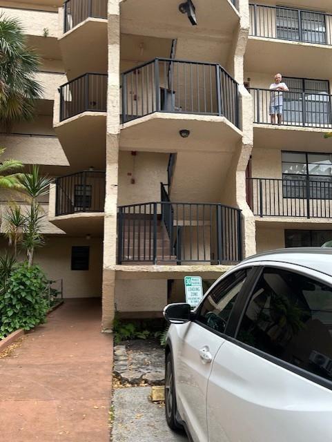 A white car is parked in front of a multi-story apartment building with exterior staircases — 3590 Blue Lake Drive # 305, Pompano Beach FL 33064, POMPANO BEACH, FL