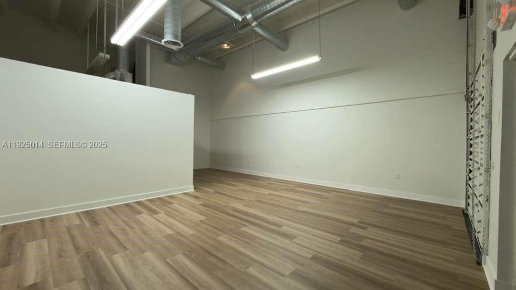 An empty room features light wood-look flooring, white walls, and exposed industrial ceiling ductwork — 1671 W 37th St # 1, Hialeah FL 33012, HIALEAH, FL