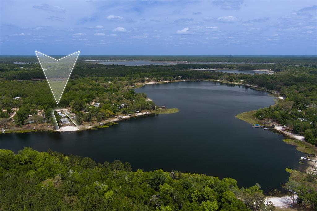 An aerial view shows a waterfront house on a lake surrounded by dense forest — 8491 LILLY LAKE ROAD, MELROSE, FL