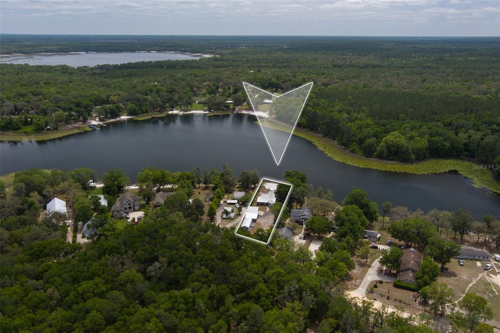 An aerial view shows a house on a lakefront lot surrounded by dense trees — 8491 LILLY LAKE ROAD, MELROSE, FL