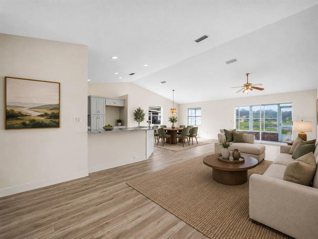 An open-concept living and dining area features light wood flooring, neutral walls, and vaulted ceilings — 6341 SILVER LAKES DRIVE W, LAKELAND, FL