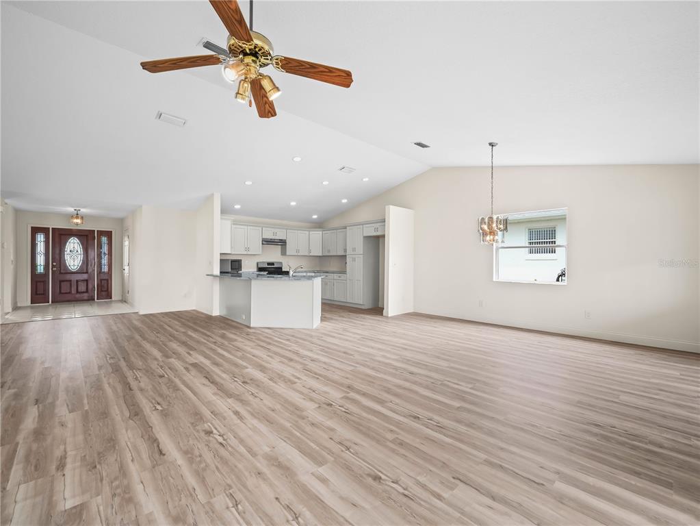 An open-concept living area features light wood-look flooring, a kitchen with white cabinets, and a ceiling fan — 6341 SILVER LAKES DRIVE W, LAKELAND, FL
