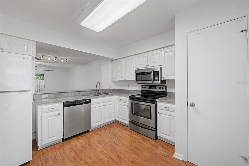 A kitchen with white cabinets, stainless steel appliances, and wood-look flooring — 13856 STONE MILL WAY, TAMPA, FL