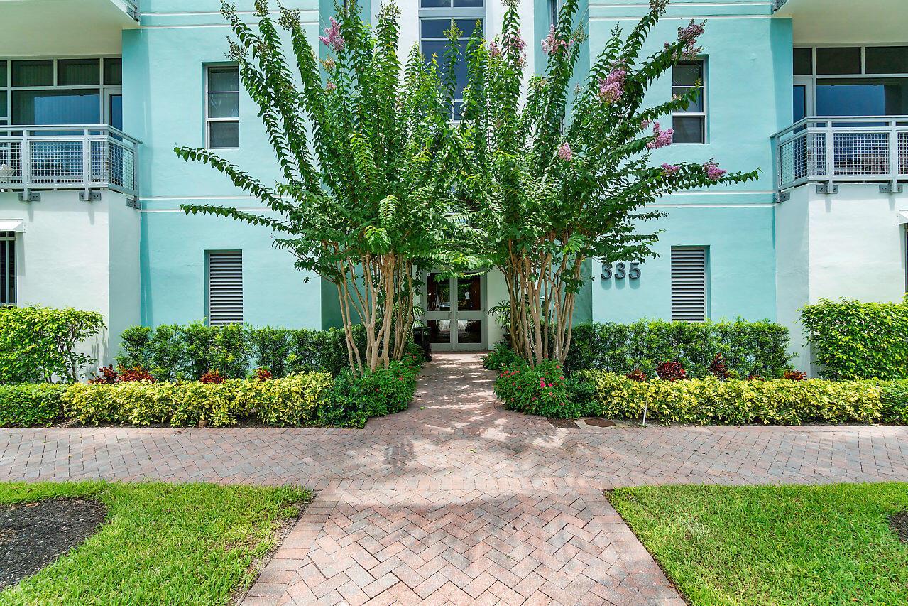 A brick walkway leads to the entrance of a light blue building with two trees — 335 SE 6th Avenue # 304, Delray Beach FL 33483, DELRAY BEACH, FL