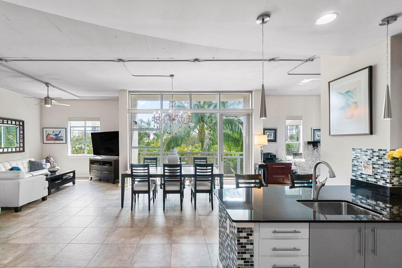 An open-concept living and dining area features tile floors, a kitchen island, and balcony access — 335 SE 6th Avenue # 304, Delray Beach FL 33483, DELRAY BEACH, FL