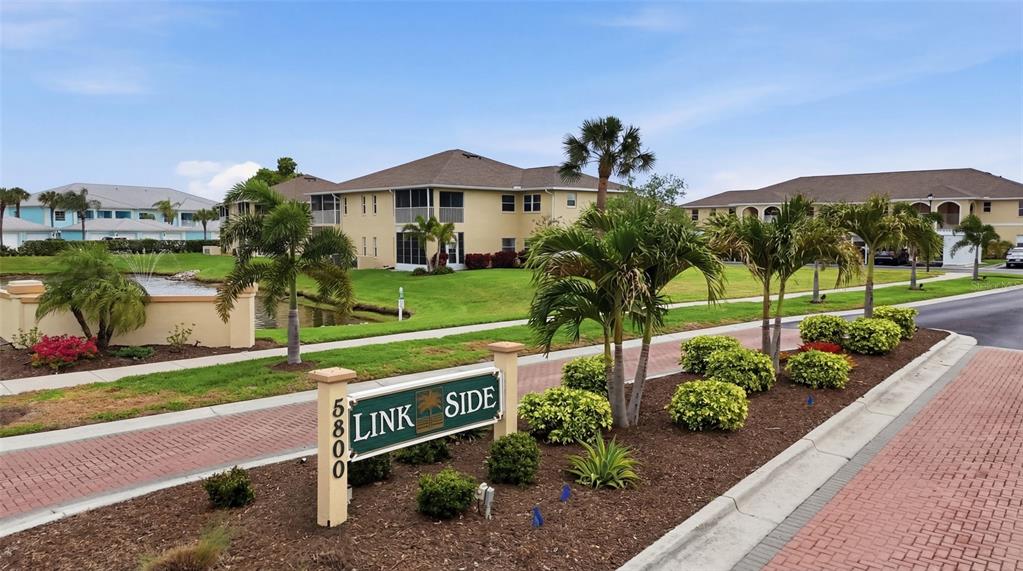 A sign for Link Side stands in front of multi-story residential buildings and palm trees — 5800 SABAL TRACE DRIVE UNIT 801, NORTH PORT, FL