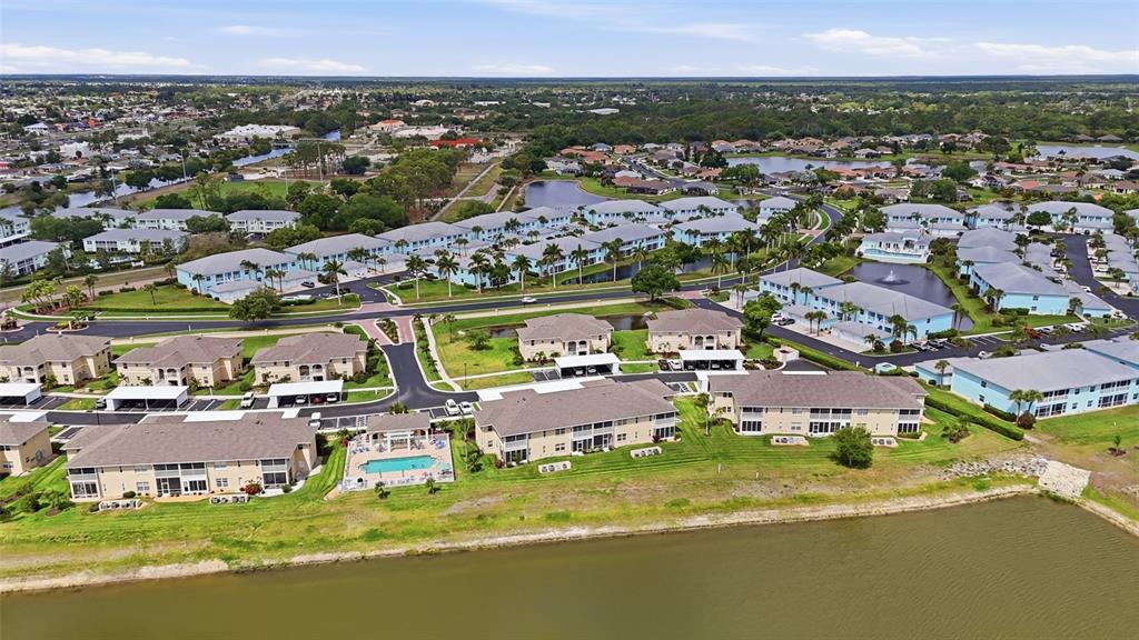 An aerial view of a residential apartment complex featuring multiple buildings, a pool, and ponds — 5800 SABAL TRACE DRIVE UNIT 801, NORTH PORT, FL