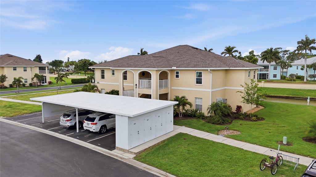 An exterior view of a two-story apartment building with a covered parking structure in front — 5800 SABAL TRACE DRIVE UNIT 801, NORTH PORT, FL