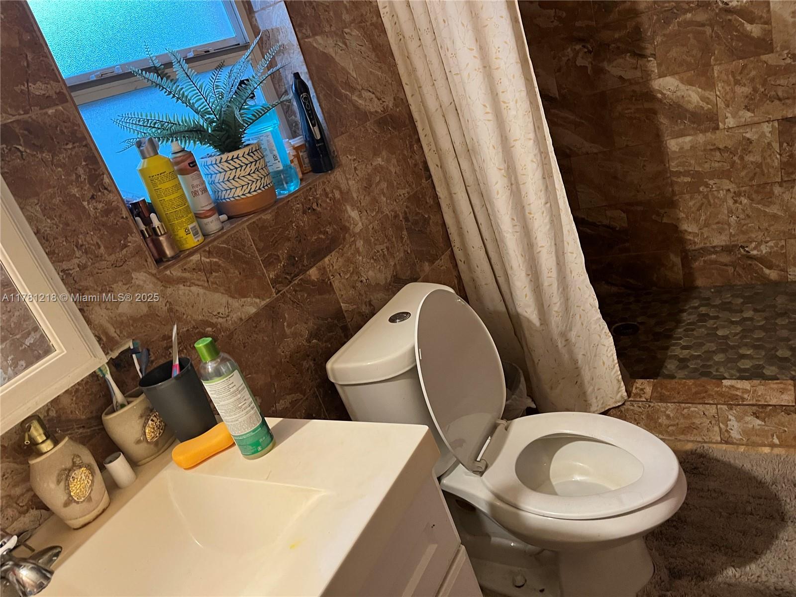 A bathroom features a white vanity, a toilet, and a shower with brown tile walls — 6546 SW 20th Ct, Miramar FL 33023, MIRAMAR, FL