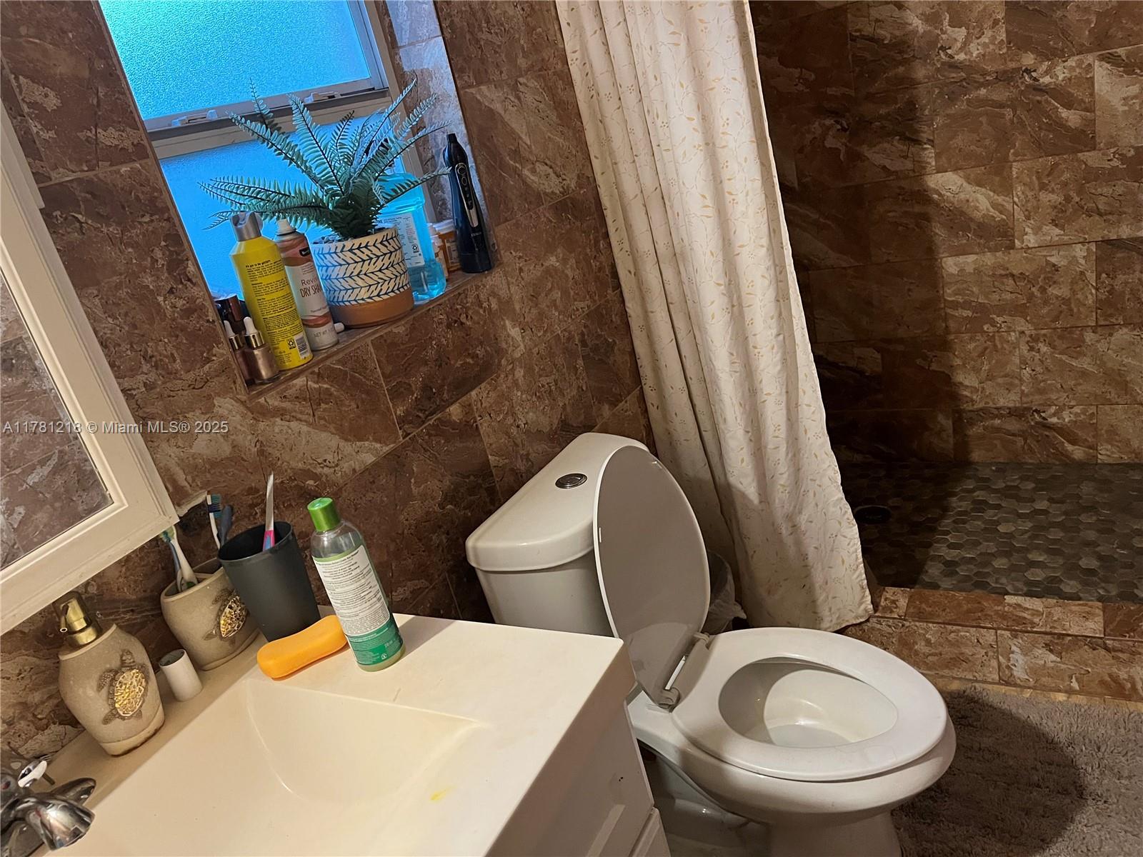 A bathroom features a white vanity, a toilet, and a shower area with brown tile — 6546 SW 20th Ct, Miramar FL 33023, MIRAMAR, FL