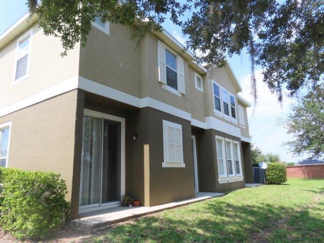The exterior of a two-story house features tan and brown stucco walls with white trim — 1971 ESTANCIA CIRCLE, KISSIMMEE, FL