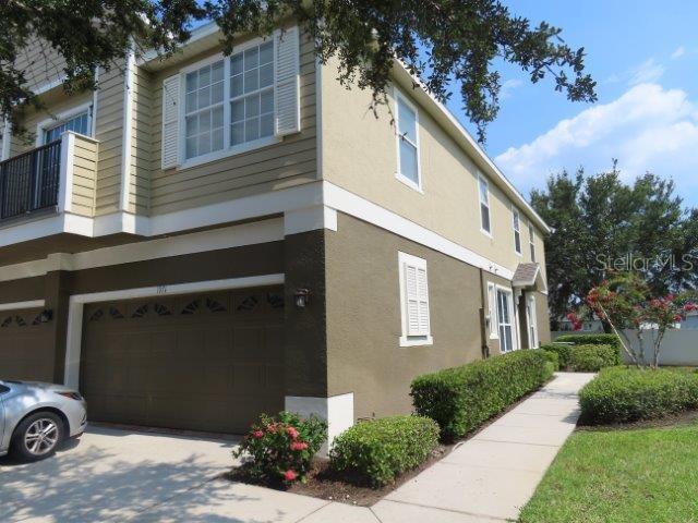 A two-story townhouse exterior features a tan and brown facade with a two-car garage — 1971 ESTANCIA CIRCLE, KISSIMMEE, FL