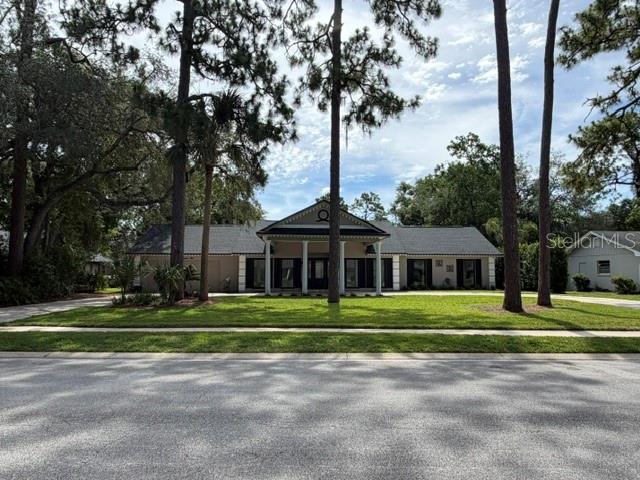 A single-story house with a covered front porch sits behind a lawn and tall trees — 210 W TIMBERCOVE CIRCLE, LONGWOOD, FL