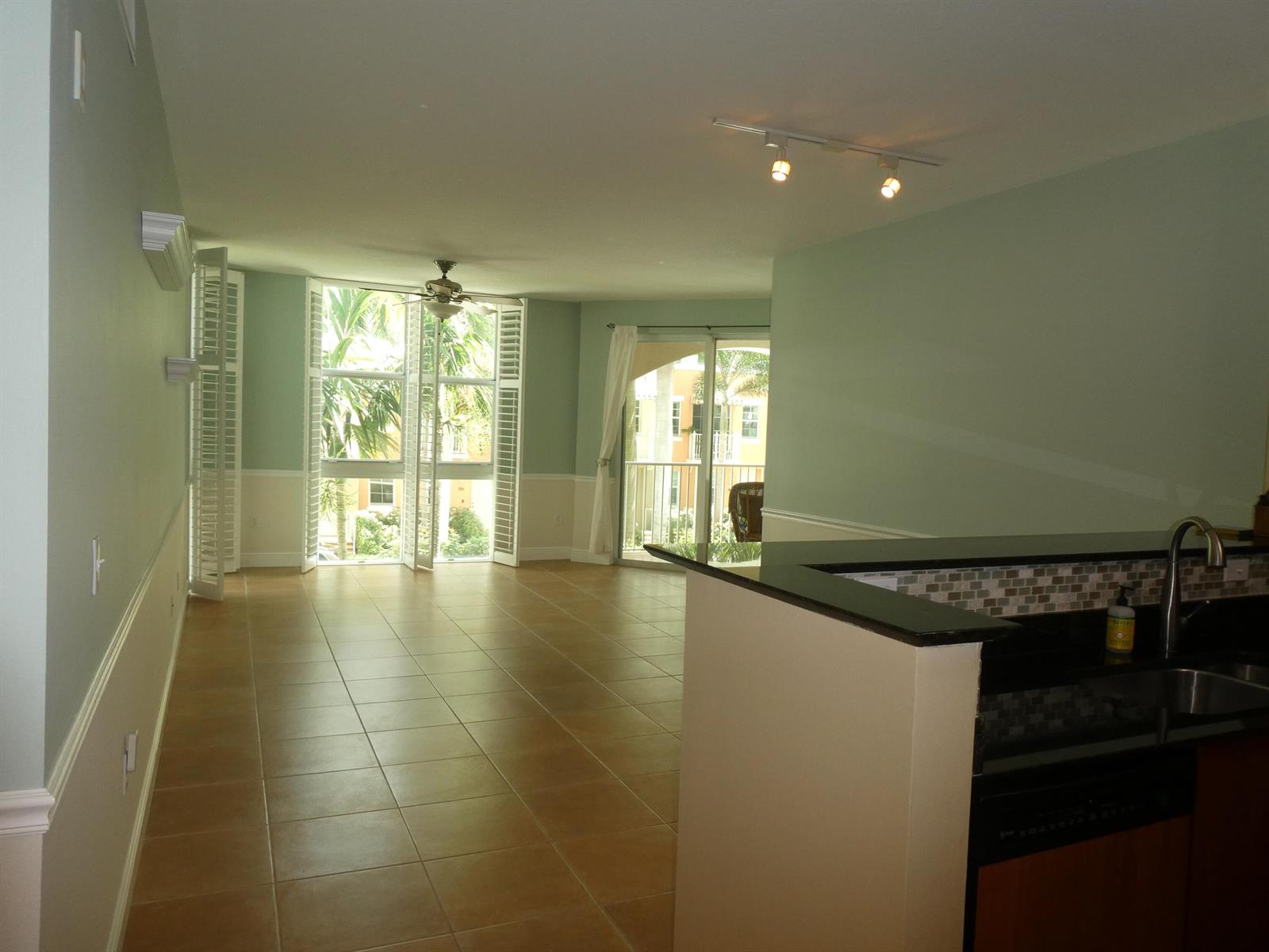An open-concept living area with tile flooring, a ceiling fan, and a kitchen breakfast bar — 804 E Windward Way # 211, Lantana FL 33462, LANTANA, FL