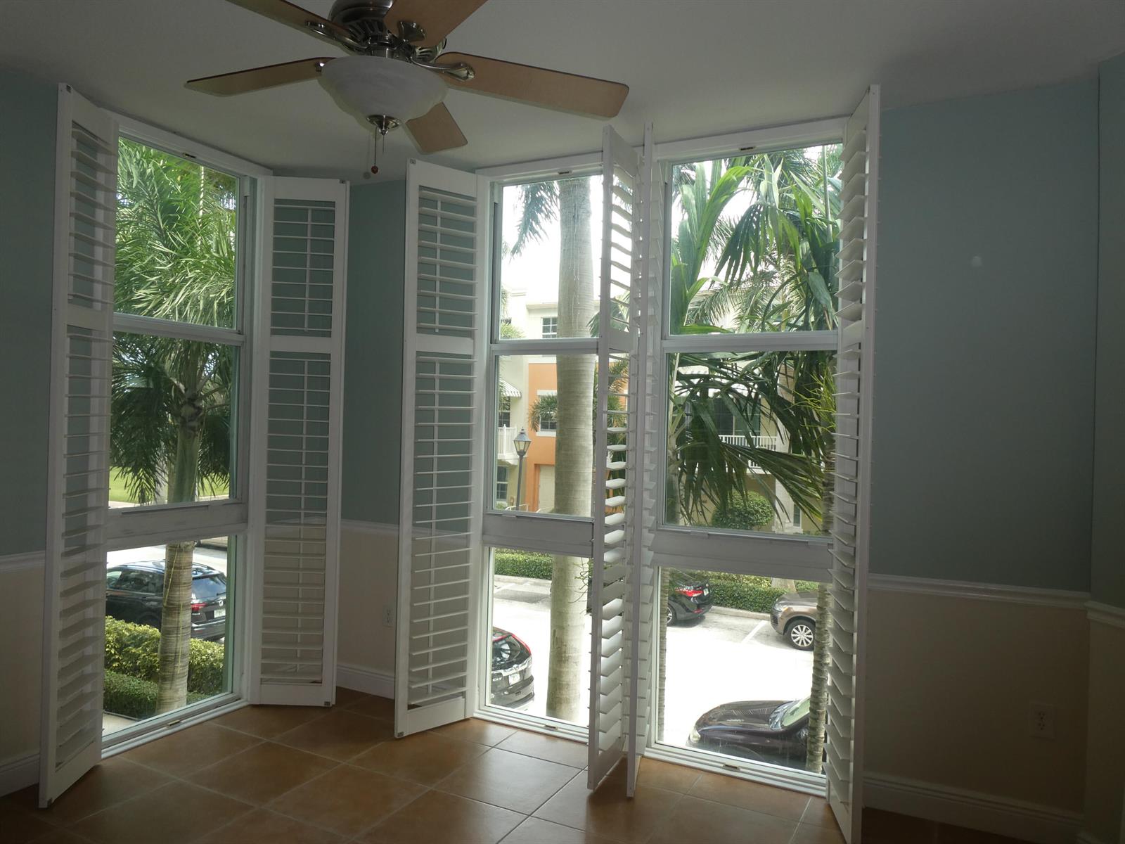 A room with tile floors, a ceiling fan, and large windows featuring white plantation shutters — 804 E Windward Way # 211, Lantana FL 33462, LANTANA, FL