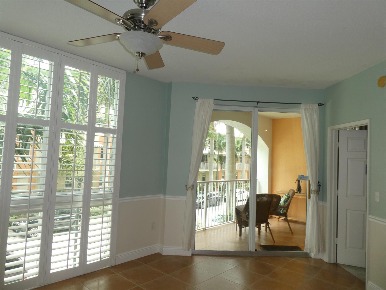 A room with light blue walls, tile flooring, a ceiling fan, and a balcony entrance — 804 E Windward Way # 211, Lantana FL 33462, LANTANA, FL
