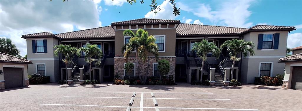 A two-story apartment building with a tiled roof, stucco exterior, and palm trees in front — 12740 SORRENTO WAY UNIT 101, BRADENTON, FL