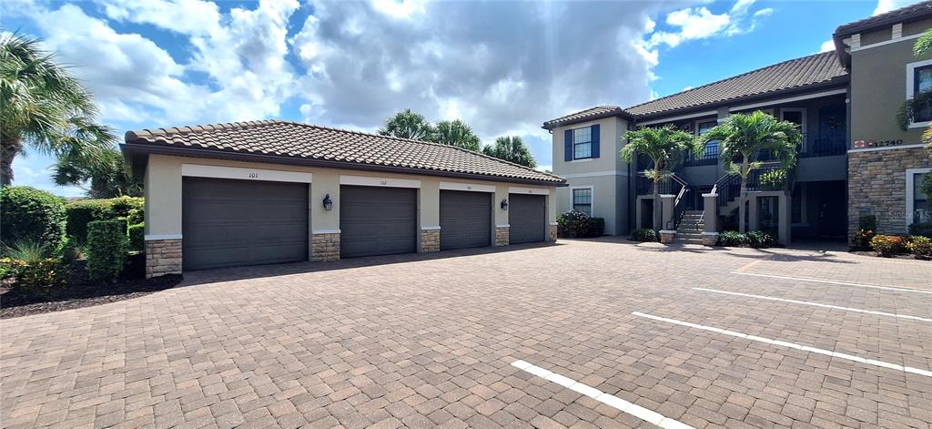A paved parking area features a detached four-car garage building next to a multi-story residence — 12740 SORRENTO WAY UNIT 101, BRADENTON, FL