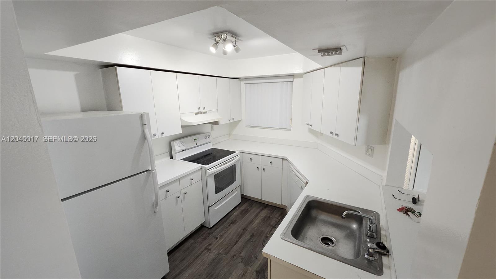 A white kitchen features white cabinets, a stainless steel sink, and dark wood-look flooring — 8305 SW 152nd Ave # 404, Miami FL 33193, MIAMI, FL