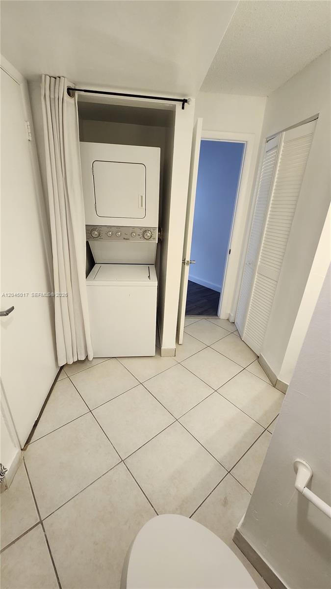 A laundry closet with a stacked washer and dryer sits in a tiled bathroom — 8305 SW 152nd Ave # 404, Miami FL 33193, MIAMI, FL