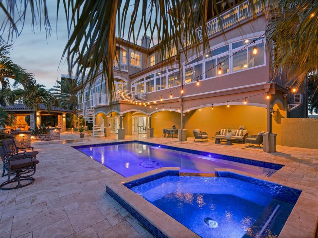 A multi-story house with a pool, hot tub, and patio area at dusk — 2057 N POINTE ALEXIS DRIVE, TARPON SPRINGS, FL