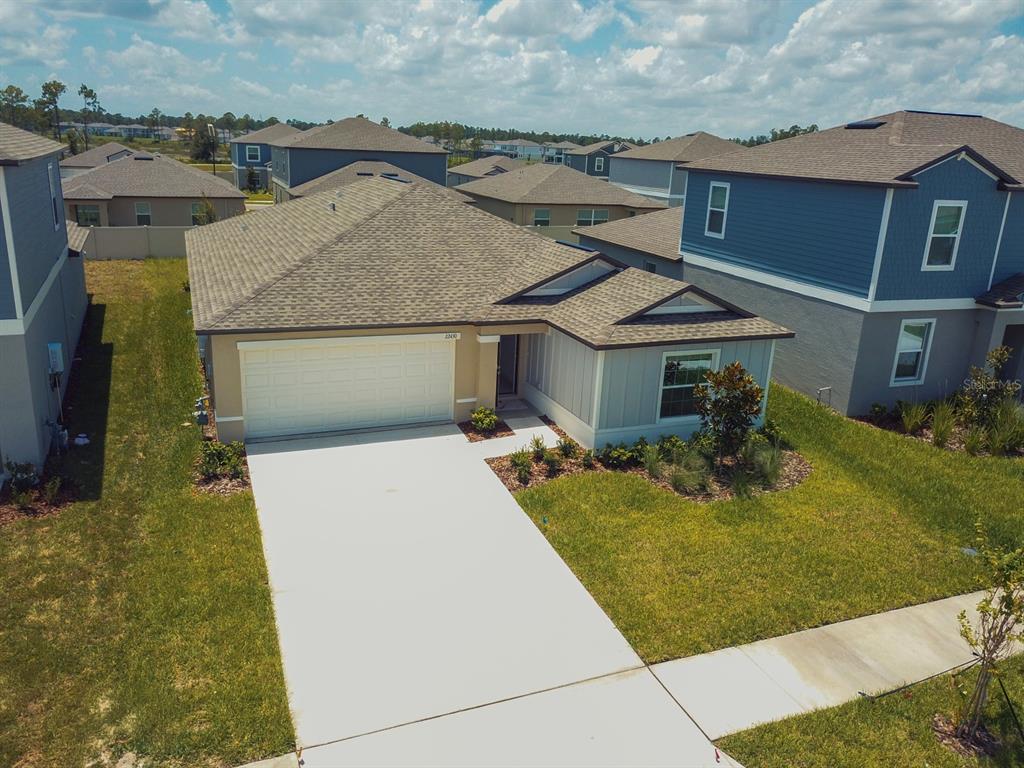 An aerial view of a single-story suburban house with a concrete driveway and tan siding — 22430 BLAZING STAR, LAND O LAKES, FL