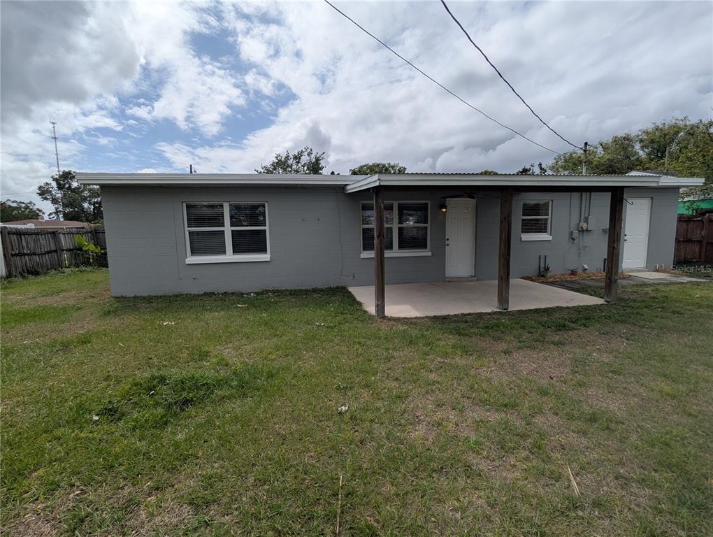 The exterior of a gray, single-story house features a covered concrete patio and a lawn — 5421 ALLOWAY STREET, ORLANDO, FL
