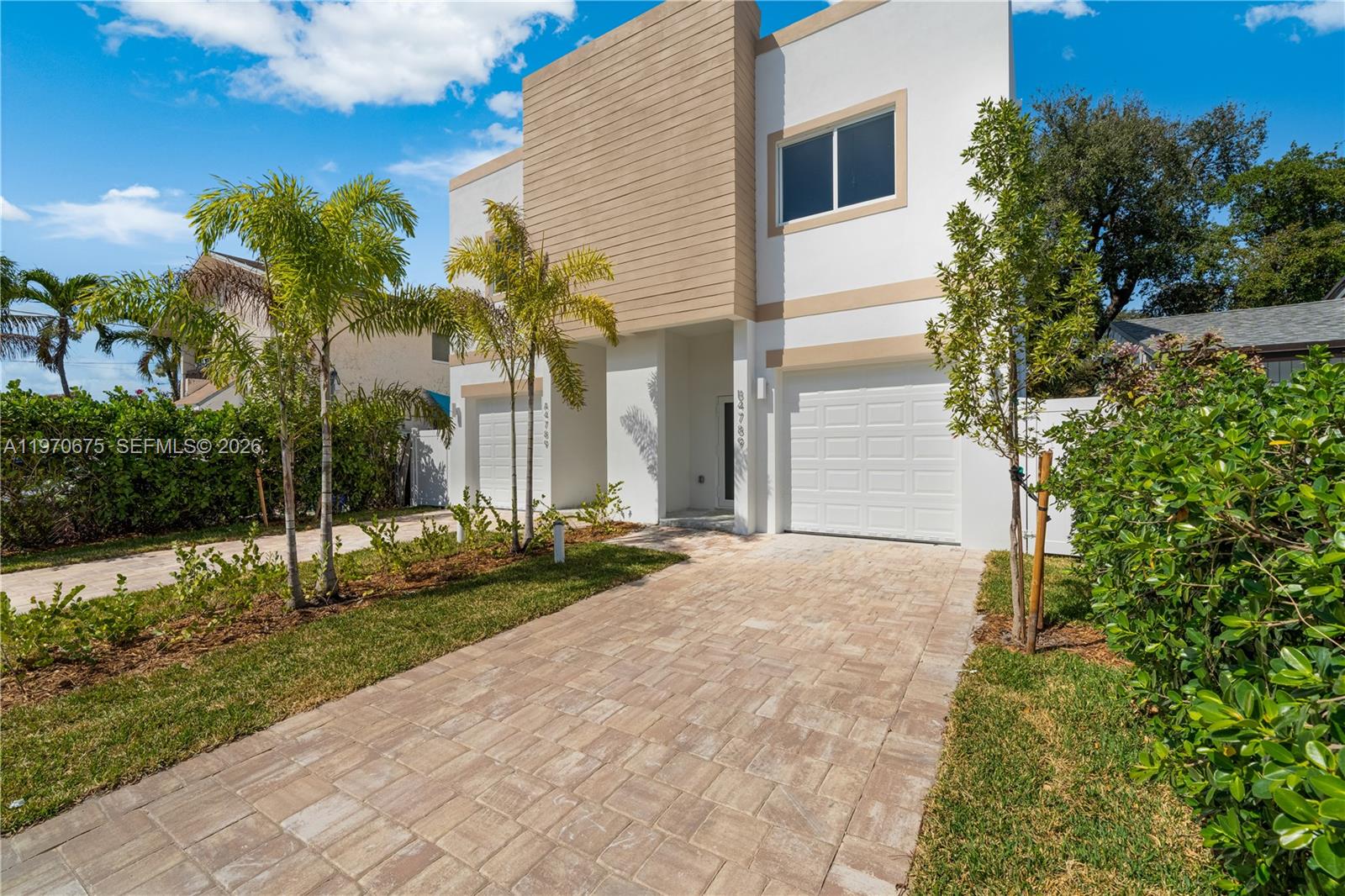 A modern two-story duplex features white stucco, tan accents, paver driveways, and palm trees — 4789 NW 1st St, Miami FL 33126, MIAMI, FL