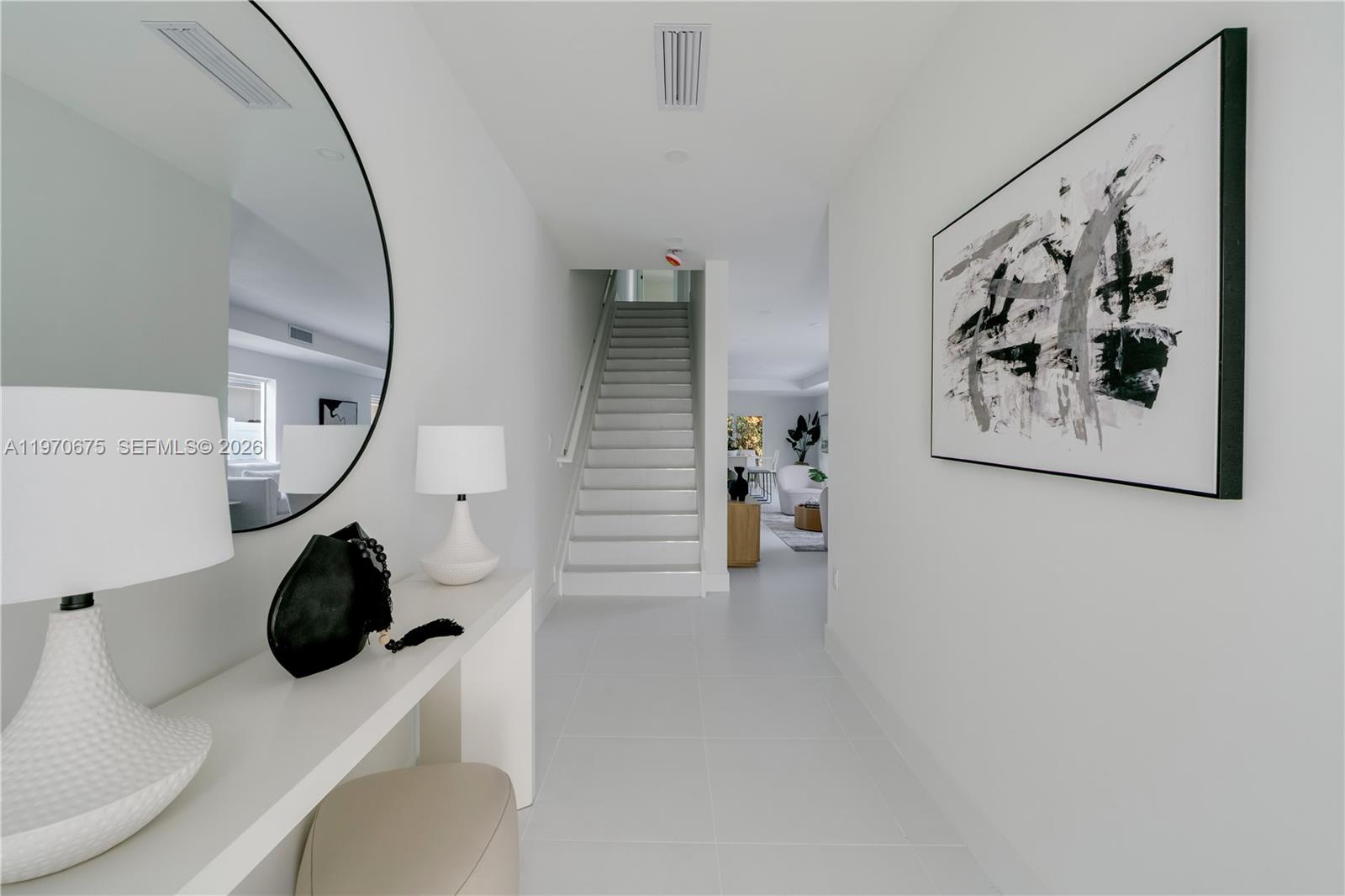 A white hallway features a staircase, a console table with lamps, and abstract wall art — 4789 NW 1st St, Miami FL 33126, MIAMI, FL