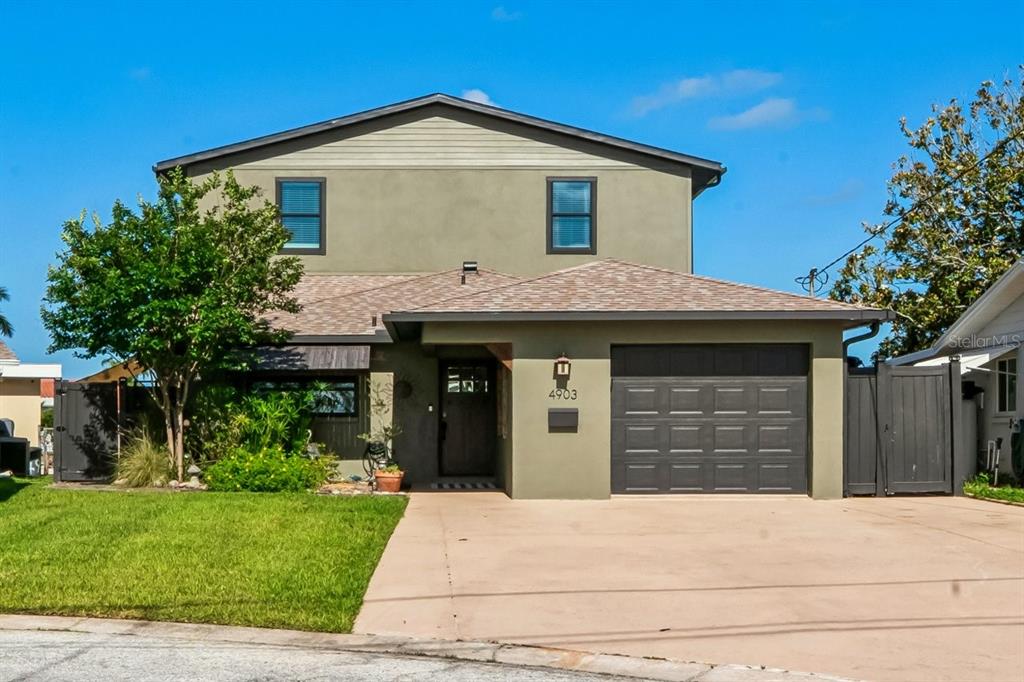 A two-story house with a tan exterior, a front-facing garage, and a green lawn — 4903 BLUE HERON DRIVE, NEW PORT RICHEY, FL