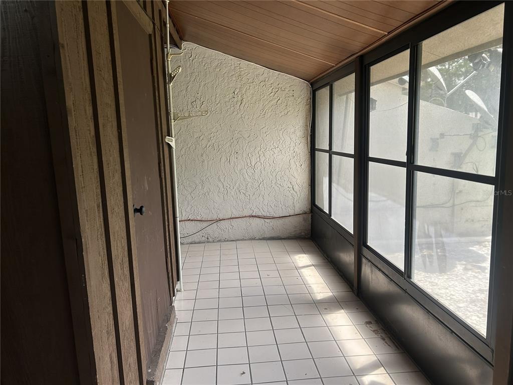 A screened-in porch features white tiled flooring, a textured wall, and a wood-paneled ceiling — 484 PRESTWICK PLACE, KISSIMMEE, FL