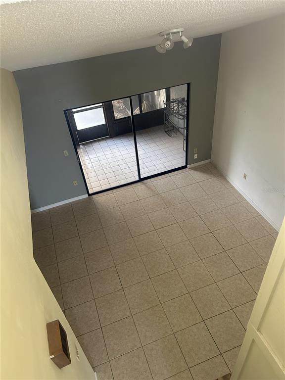 A high-angle view of a living room with tile flooring, gray walls, and sliding glass doors — 484 PRESTWICK PLACE, KISSIMMEE, FL