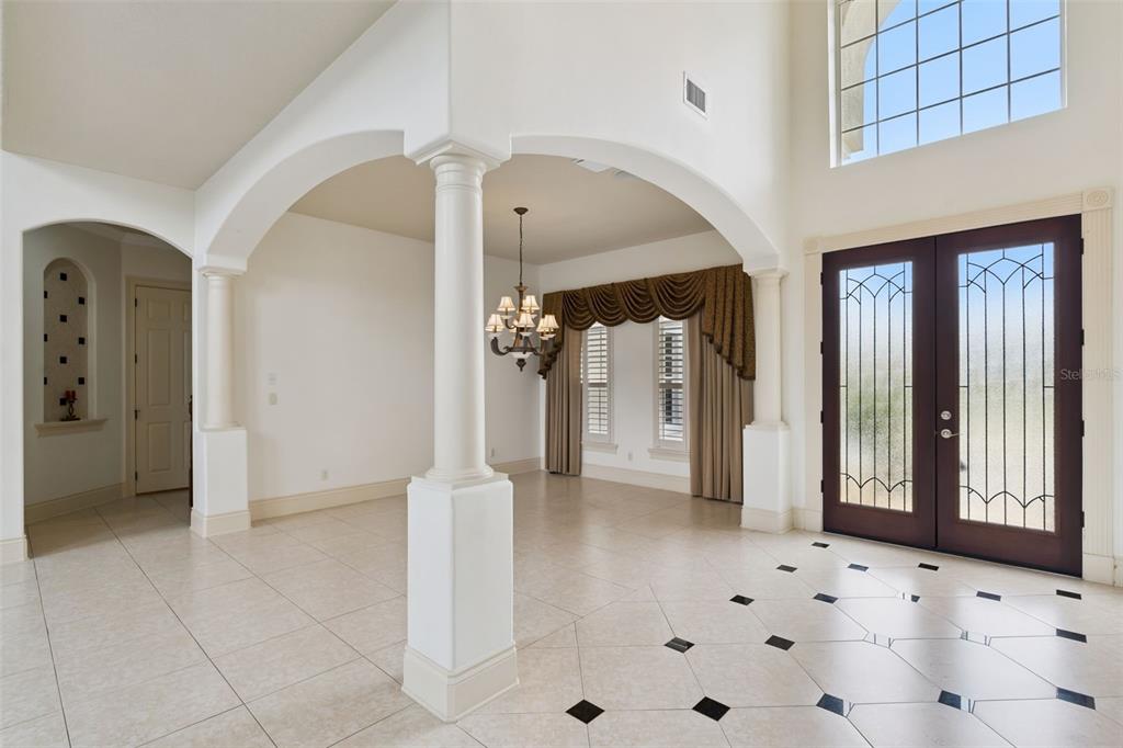 An entryway with tiled floors, arched columns, a chandelier, and double front doors — 1692 ORANGE THORPE LANE, CLERMONT, FL