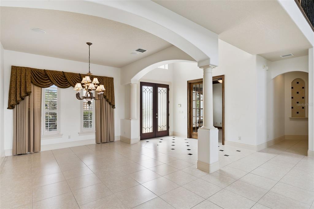A spacious foyer and dining area feature tile floors, arched architectural details, and double doors — 1692 ORANGE THORPE LANE, CLERMONT, FL