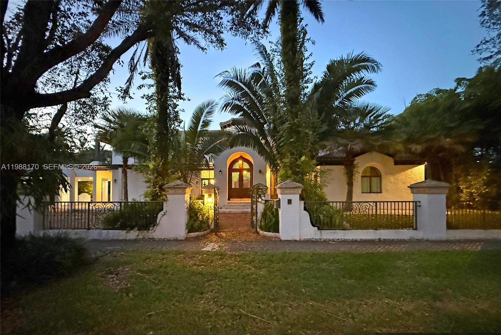 A brick walkway leads to the arched entryway of a white stucco house with palms — 1253 Sorolla Ave, Coral Gables FL 33134, CORAL GABLES, FL
